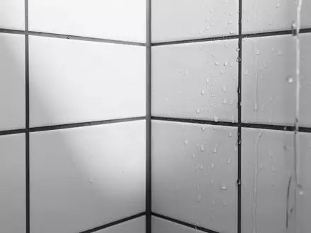 Ein minimalistisches Badezimmer mit weißen Fliesen und weichem Lichteinfall, das die feuchte Umgebung symbolisiert. - Foto: über boerse-global.de
