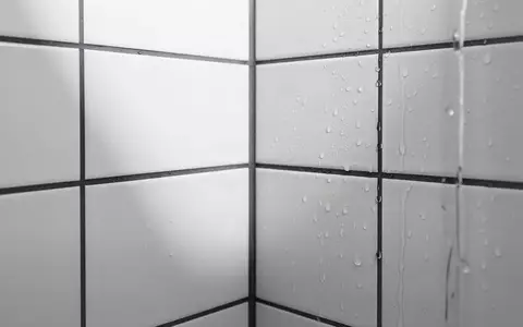Ein minimalistisches Badezimmer mit weißen Fliesen und weichem Lichteinfall, das die feuchte Umgebung symbolisiert. - Foto: über boerse-global.de