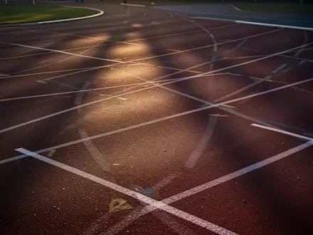 Leere Laufbahn eines Stadions in der Abenddämmerung zur Symbolisierung von mentaler Ausdauer und Fokus im Leistungssport. - Foto: über boerse-global.de