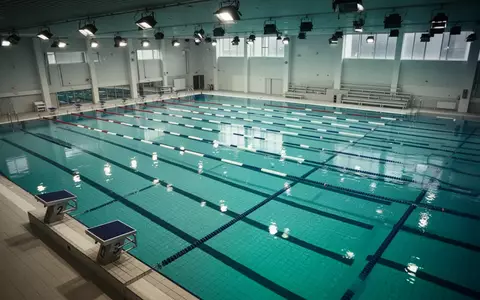 Ein modernes, leeres Hallenbad mit klaren Bahnen und reflektierendem Wasser. - Foto: über boerse-global.de