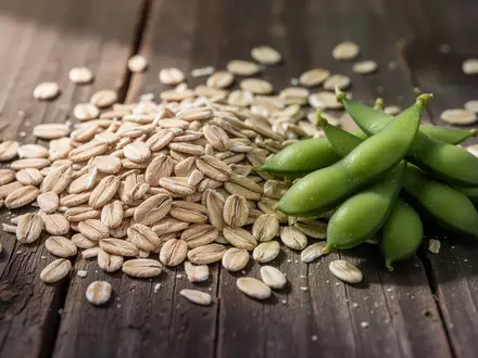 Nahaufnahme von rohen Haferkörnern und frischen Edamame-Schoten auf einer dunklen Holzoberfläche. - Foto: über boerse-global.de