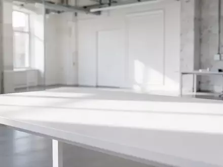 Ein minimalistischer, heller Arbeitsplatz mit einer leeren weißen Schreibtischoberfläche und dezenter, moderner Architektur im Hintergrund. - Foto: über boerse-global.de