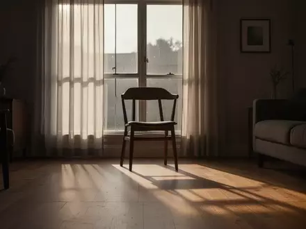 Ein einsamer, leerer Stuhl in einem schattigen Wohnzimmer bei sanftem Tageslicht, das durch ein Fenster fällt. - Foto: über boerse-global.de