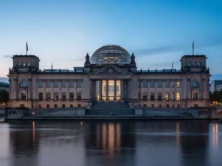 Das Reichstagsgebäude in Berlin bei Dämmerung, aufgenommen von der Spree aus mit Fokus auf die Architektur. - Foto: über boerse-global.de