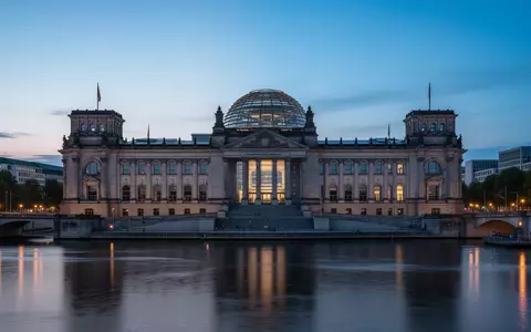 Das Reichstagsgebäude in Berlin bei Dämmerung, aufgenommen von der Spree aus mit Fokus auf die Architektur. - Foto: über boerse-global.de