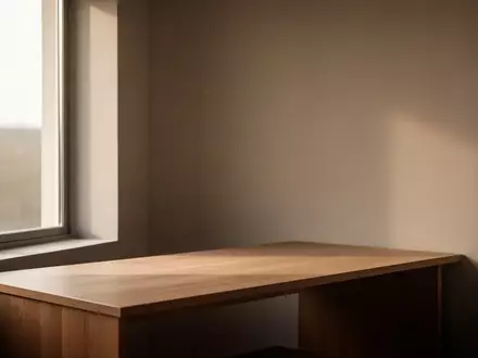 Ein minimalistischer Arbeitsplatz mit leerem Schreibtisch und natürlichem Lichteinfall in einem ruhigen Raum. - Foto: über boerse-global.de