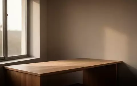 Ein minimalistischer Arbeitsplatz mit leerem Schreibtisch und natürlichem Lichteinfall in einem ruhigen Raum. - Foto: über boerse-global.de