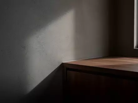 Ein minimalistisch eingerichtetes Hotelzimmer mit Fokus auf Wandtexturen und Lichtschatten in einer Raumecke. - Foto: über boerse-global.de