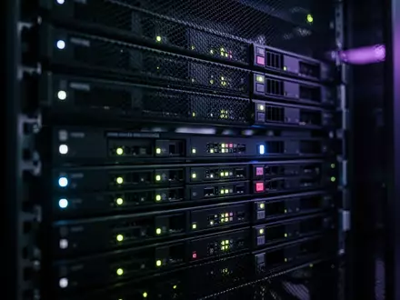 Dunkler Serverraum mit leuchtenden Status-LEDs in einem Rack. - Foto: über boerse-global.de