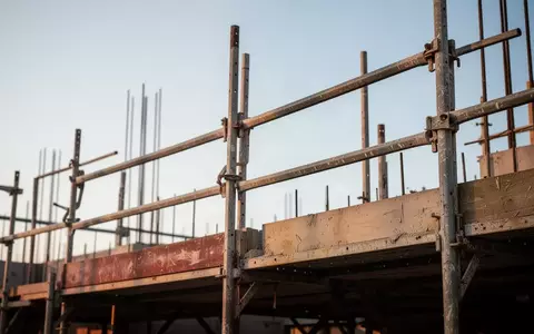Ein Baugerüst vor einem klaren Himmel, das die körperliche Belastung im Handwerk symbolisiert. - Foto: über boerse-global.de