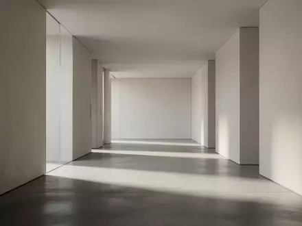 Ein minimalistischer, leerer Flur mit klaren architektonischen Linien und sanftem Lichteinfall auf einem Betonboden. - Foto: über boerse-global.de