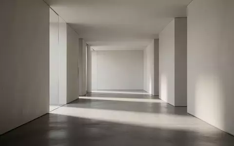 Ein minimalistischer, leerer Flur mit klaren architektonischen Linien und sanftem Lichteinfall auf einem Betonboden. - Foto: über boerse-global.de