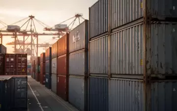 Ein moderner Containerterminal in der Abenddämmerung mit gestapelten Schiffscontainern bei natürlichem Licht. - Foto: über boerse-global.de