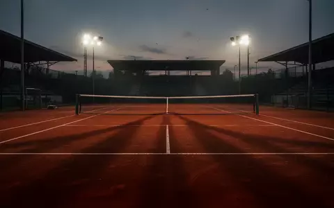 Ein verlassener Tennisplatz in der Dämmerung mit langen Schatten auf dem roten Sand. - Foto: über boerse-global.de