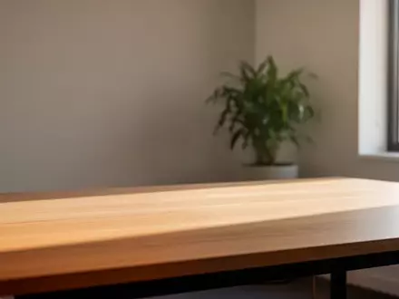 Ein minimalistischer, aufgeräumter Arbeitsplatz mit einem Holztisch und einer Pflanze im sanften natürlichen Licht. - Foto: über boerse-global.de