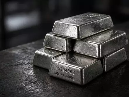 Ein Stapel glänzender Silberbarren auf einem dunklen industriellen Tisch in stimmungsvollem Licht. - Foto: über boerse-global.de