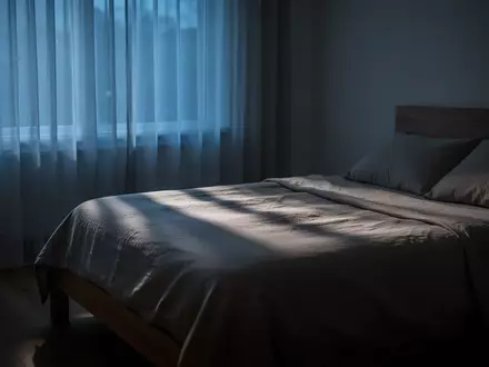 Ein minimalistisch eingerichtetes, ruhig wirkendes Schlafzimmer in den frühen Morgenstunden mit sanftem, natürlichem Licht. - Foto: über boerse-global.de