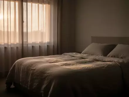 Ein unbewohntes Schlafzimmer in den frühen Morgenstunden mit sanftem Tageslicht, das auf ein unbenutztes, ordentliches Bett fällt. - Foto: über boerse-global.de