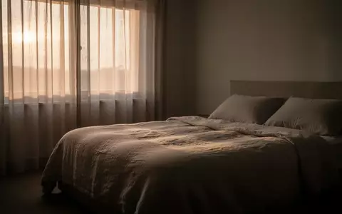 Ein unbewohntes Schlafzimmer in den frühen Morgenstunden mit sanftem Tageslicht, das auf ein unbenutztes, ordentliches Bett fällt. - Foto: über boerse-global.de