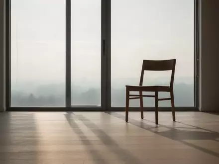Ein minimalistischer, leerer Raum mit einem einzelnen Holzstuhl in der Nähe eines großen Fensters bei sanftem Morgenlicht. - Foto: über boerse-global.de