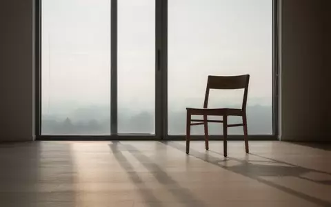 Ein minimalistischer, leerer Raum mit einem einzelnen Holzstuhl in der Nähe eines großen Fensters bei sanftem Morgenlicht. - Foto: über boerse-global.de