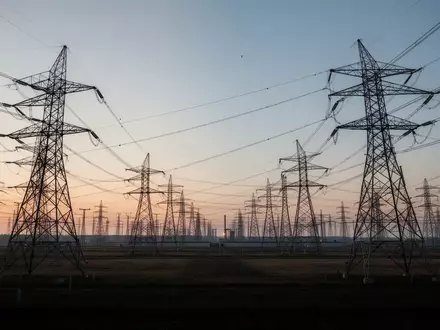 Hochspannungsleitungen und Strommasten auf einem weitläufigen Industriegelände bei Dämmerung. - Foto: über boerse-global.de
