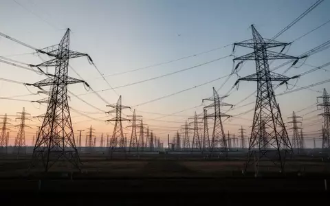 Hochspannungsleitungen und Strommasten auf einem weitläufigen Industriegelände bei Dämmerung. - Foto: über boerse-global.de