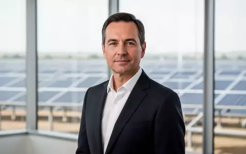 Ein professionell gekleideter Manager in einem modernen Büro mit Blick auf einen Solarpark im Hintergrund. - Foto: über boerse-global.de