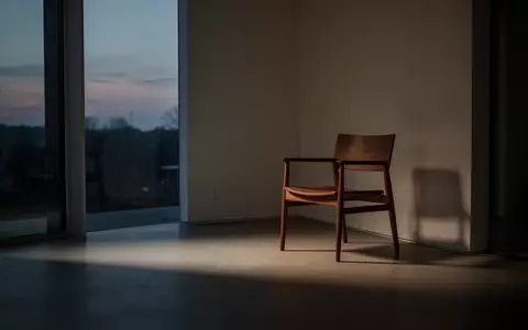 Ein leerer Holzstuhl in einem minimalistischen, schattigen Raum bei DĂ€mmerlicht, der eine AtmosphĂ€re der Erschöpfung vermittelt. - Foto: ĂŒber boerse-global.de