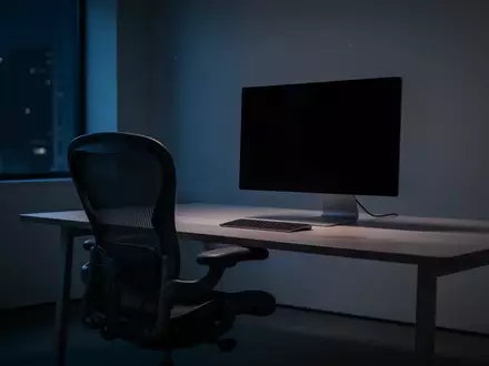 Ein leerer Arbeitsplatz mit einem dunklen Monitor in einem abgedunkelten Büro bei Nacht. - Foto: über boerse-global.de