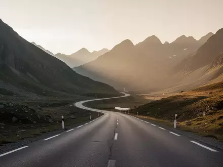 Eine einsame, kurvenreiche Bergstraße in einer weiten, minimalistischen Naturlandschaft bei Sonnenuntergang. - Foto: über boerse-global.de