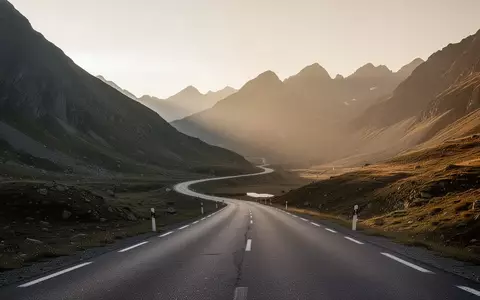 Eine einsame, kurvenreiche Bergstraße in einer weiten, minimalistischen Naturlandschaft bei Sonnenuntergang. - Foto: über boerse-global.de