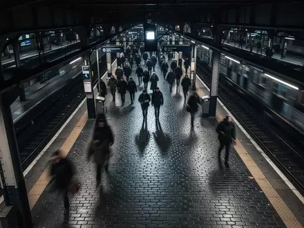 Ein belebter, nächtlicher Bahnsteig in einem Bahnhof mit unscharfen Silhouetten von Passanten in einer städtischen Umgebung. - Foto: über boerse-global.de