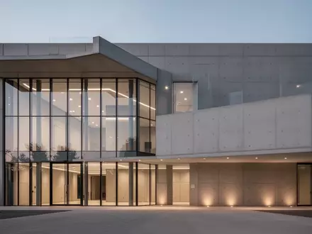 Modernes Gebäude mit Glas- und Betonfassade in der Dämmerung als Symbol für die neue Leitstelleninfrastruktur. - Foto: über boerse-global.de
