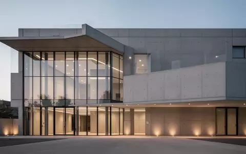 Modernes Gebäude mit Glas- und Betonfassade in der Dämmerung als Symbol für die neue Leitstelleninfrastruktur. - Foto: über boerse-global.de