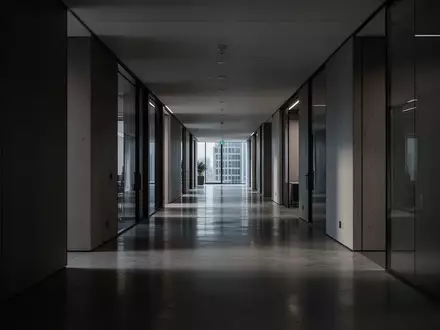 Ein menschenleerer, modern gestalteter Flur in einem Bürogebäude mit klaren Linien und gedimmtem Licht. - Foto: über boerse-global.de