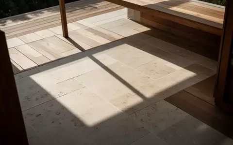 Sonnige Terrasse mit geometrischem Schattenwurf auf einem Steinboden ohne Möbel. - Foto: über boerse-global.de