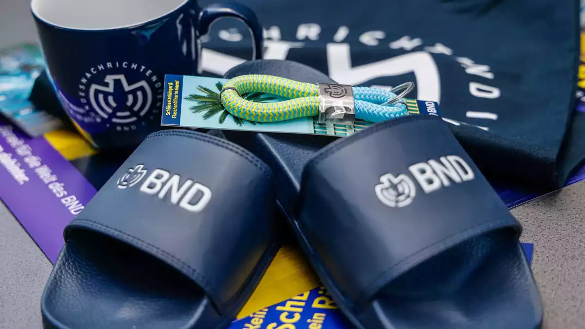 Im Merchandise-Shop gibt es T-Shirts und auch Badelatschen mit BND-Logo.  - Bild: Focke Strangmann/dpa