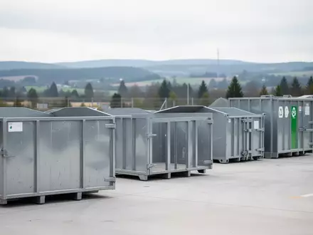 Leere, industrielle Metallcontainer auf einem aufgeräumten Wertstoffhof unter Tageslicht. - Foto: über boerse-global.de