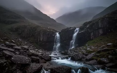 Eine neblige, zerklüftete Berglandschaft im Lake District bei Dämmerung mit einem reißenden Gebirgsbach. - Foto: über boerse-global.de