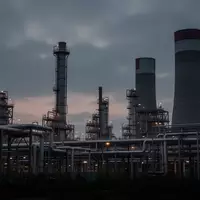 Ein weitläufiges Industrieareal mit Raffinerieanlagen in der Dämmerung unter einem bewölkten Himmel. - Foto: über boerse-global.de