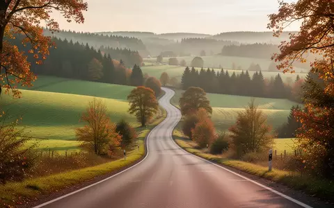 Eine weitläufige, herbstliche Landschaft mit einer kurvigen Landstraße durch die Hügel Baden-Württembergs bei Sonnenaufgang. - Foto: über boerse-global.de