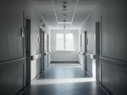 Ein langer, leerer Krankenhausflur mit weißen Wänden und diffusem Tageslicht, der eine ruhige und sterile Atmosphäre vermittelt. - Foto: über boerse-global.de