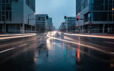 Eine nächtliche, verregnete Straßenkreuzung in einer modernen Stadt mit verschwommenen Lichtspuren des Verkehrs. - Foto: über boerse-global.de