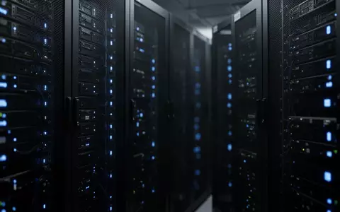 Dunkler Serverraum mit abstrakten Reihen von Netzwerkschränken und dezenten blauen Statusleuchten. - Foto: über boerse-global.de