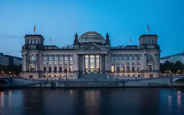 Das Berliner Reichstagsgebäude in der Dämmerung, aufgenommen aus der Ferne über die Spree. - Foto: über boerse-global.de