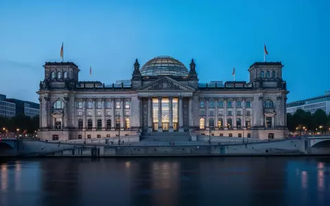Das Berliner Reichstagsgebäude in der Dämmerung, aufgenommen aus der Ferne über die Spree. - Foto: über boerse-global.de