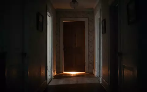 Ein stiller Flur in einem Wohnhaus bei Nacht mit warmem Licht, das unter einer geschlossenen ZimmertĂŒr hervorscheint. - Foto: ĂŒber boerse-global.de