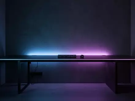 Ein minimalistischer, moderner Gaming-Bereich mit sanfter, bläulicher Beleuchtung an einer dunklen Wand. - Foto: über boerse-global.de