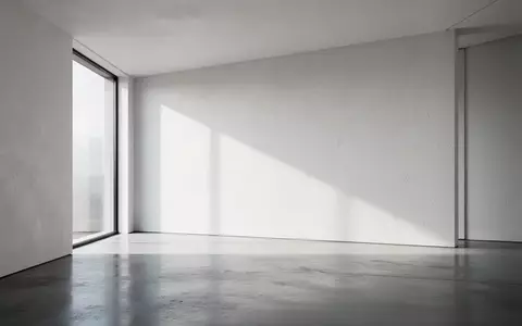 Ein minimalistischer, moderner Innenraum mit klaren Linien und weichem Tageslicht, das durch ein großes Fenster fällt. - Foto: über boerse-global.de